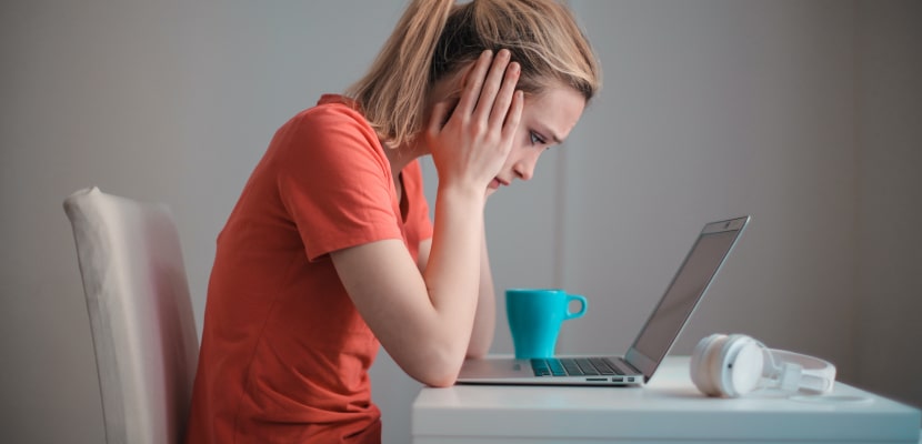 Eine Mitarbeiterin sitzt wegen einer Abmahnung frustriert vor ihrem Laptop.