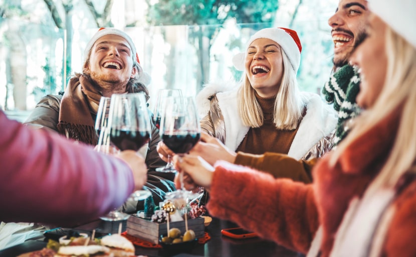 Kolleginnen stoßen mit einem Glas Rotwein auf einer Firmen Weihnachtsfeier an.