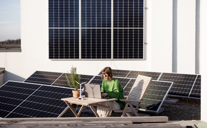 Eine Mitarbeiterin arbeitet auf einer Dachterrasse mit Solarpanels.
