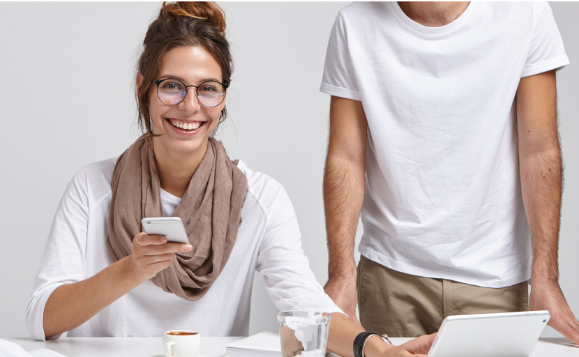 Eine lächelnde Mitarbeiterin arbeitet zusammen mit einem Kollegen am Social Media Auftritt der Arbeitgebermarke.