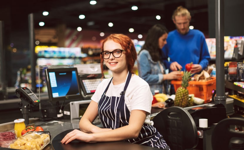 Eine junge Frau geht als Kassiererin im Supermarkt einem Minijiob nach.